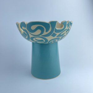 An elevated bowl with featuring a scalloped rim cut with flowing calligraphy motifs