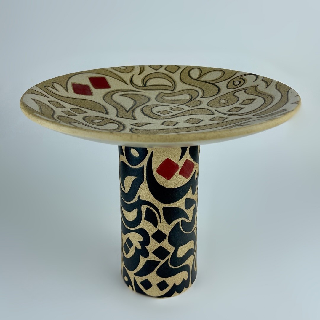 A pedestal plate on a sturdy cylindrical stem featuring contrasting calligraphy