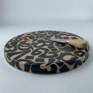 A cylindricalical cheese platter featuring a calligraphic design with flowing black forms