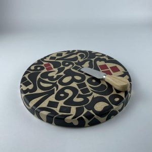 A cylindricalical cheese platter featuring a calligraphic design with flowing black forms
