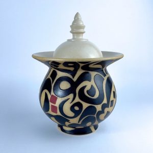 A cookie jar featuring a solid beige lid over a wide neck with contrasting calligraphy motifs