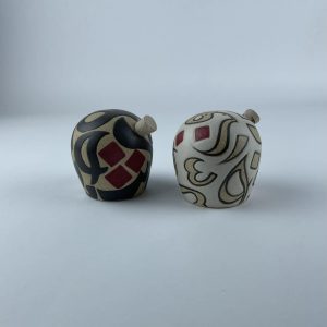 A set of two salt and pepper shakers featuring contrasting black and beige calligraphy with subtle red accents