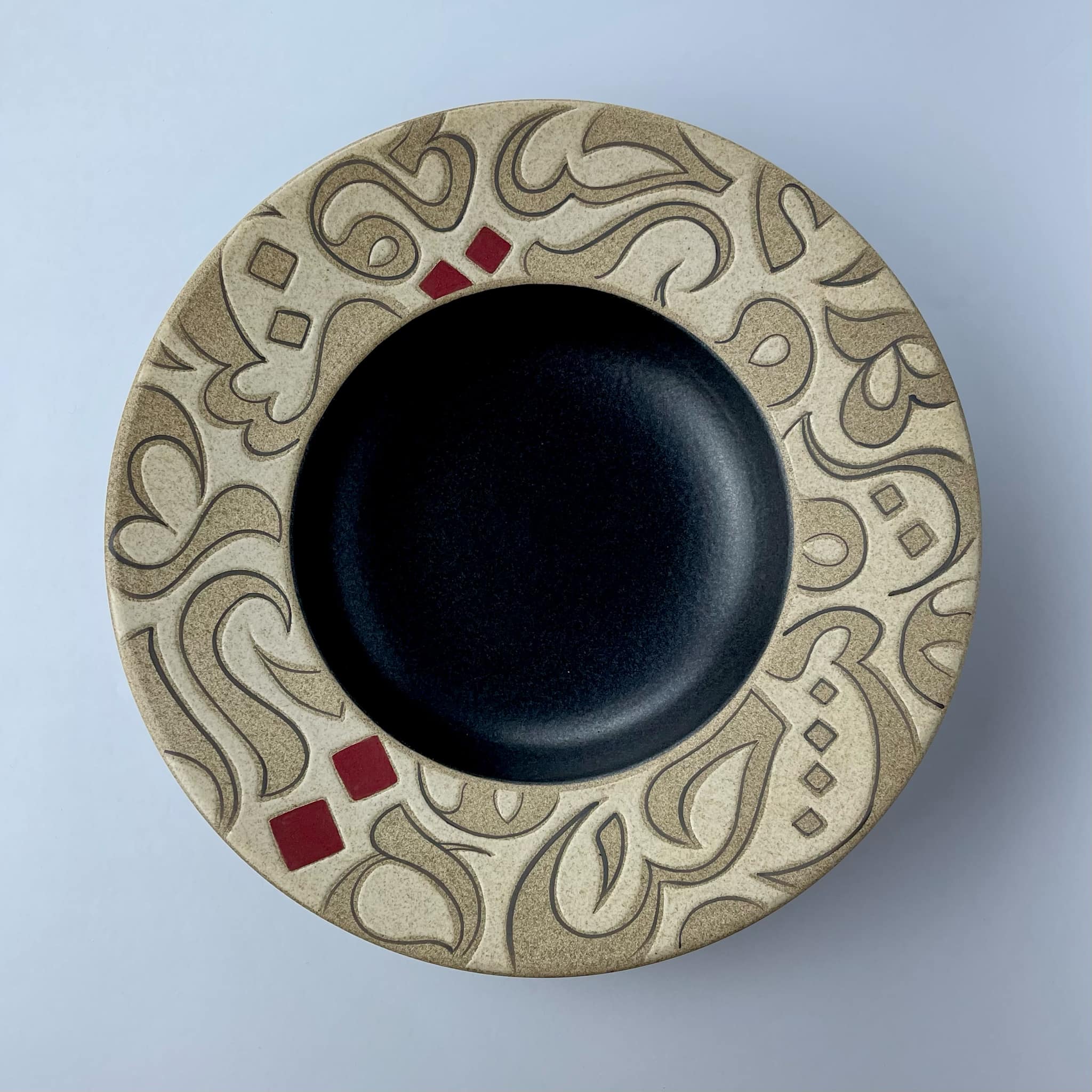 A rimmed plate featuring calligraphy motifs