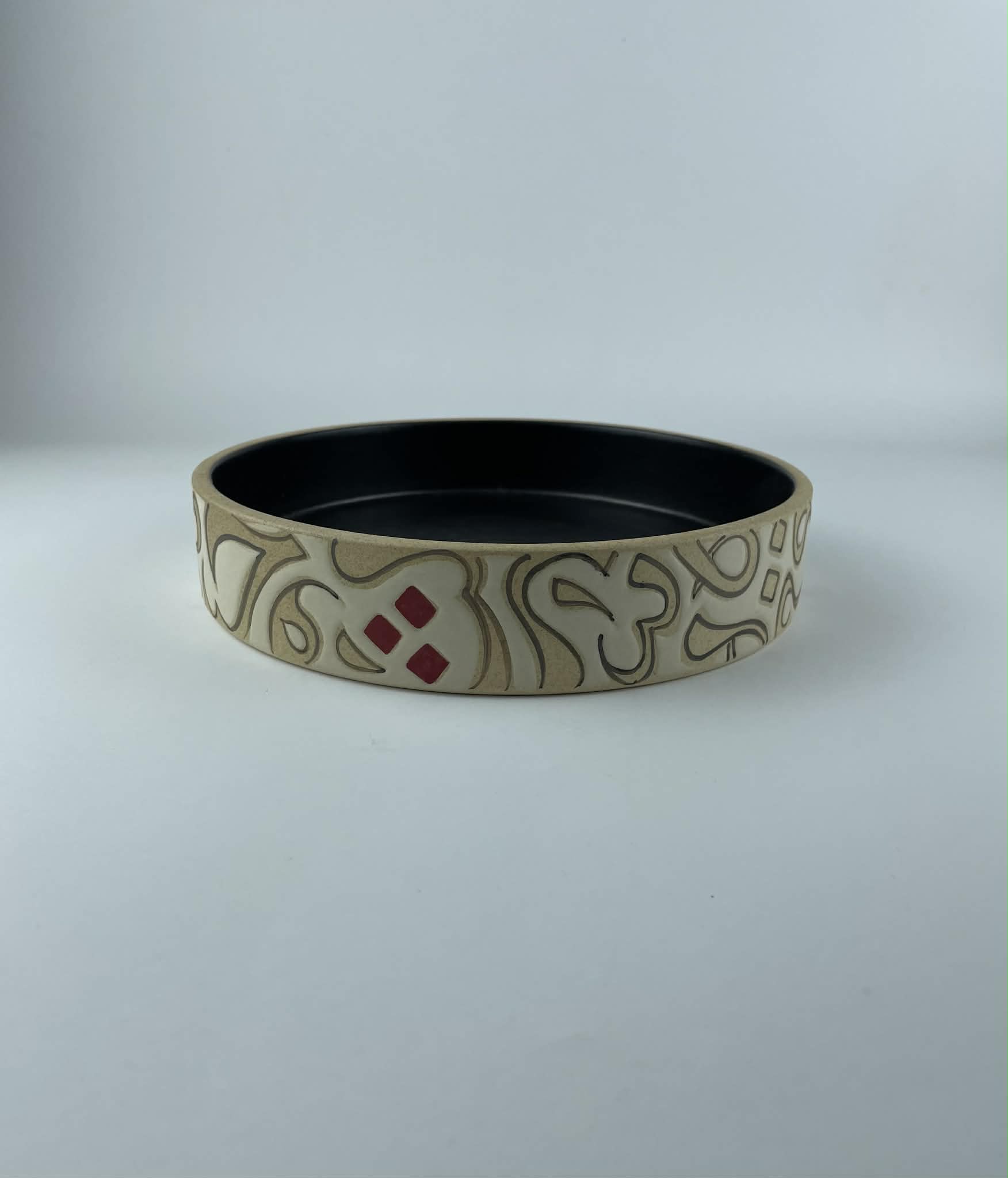 A cylindrical bowl featuring a calligraphy design with flowing beige forms on an earthy background