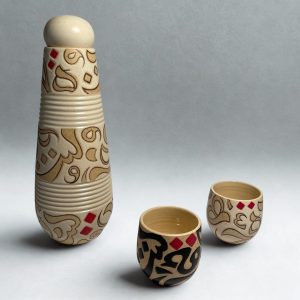 A contrasting carafe and four tumblers set with black and beige calligraphy forms. Ideal for serving beverages.
