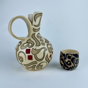 A contrasting ewer and four tumblers set with black and beige calligraphy and subtle red accents.