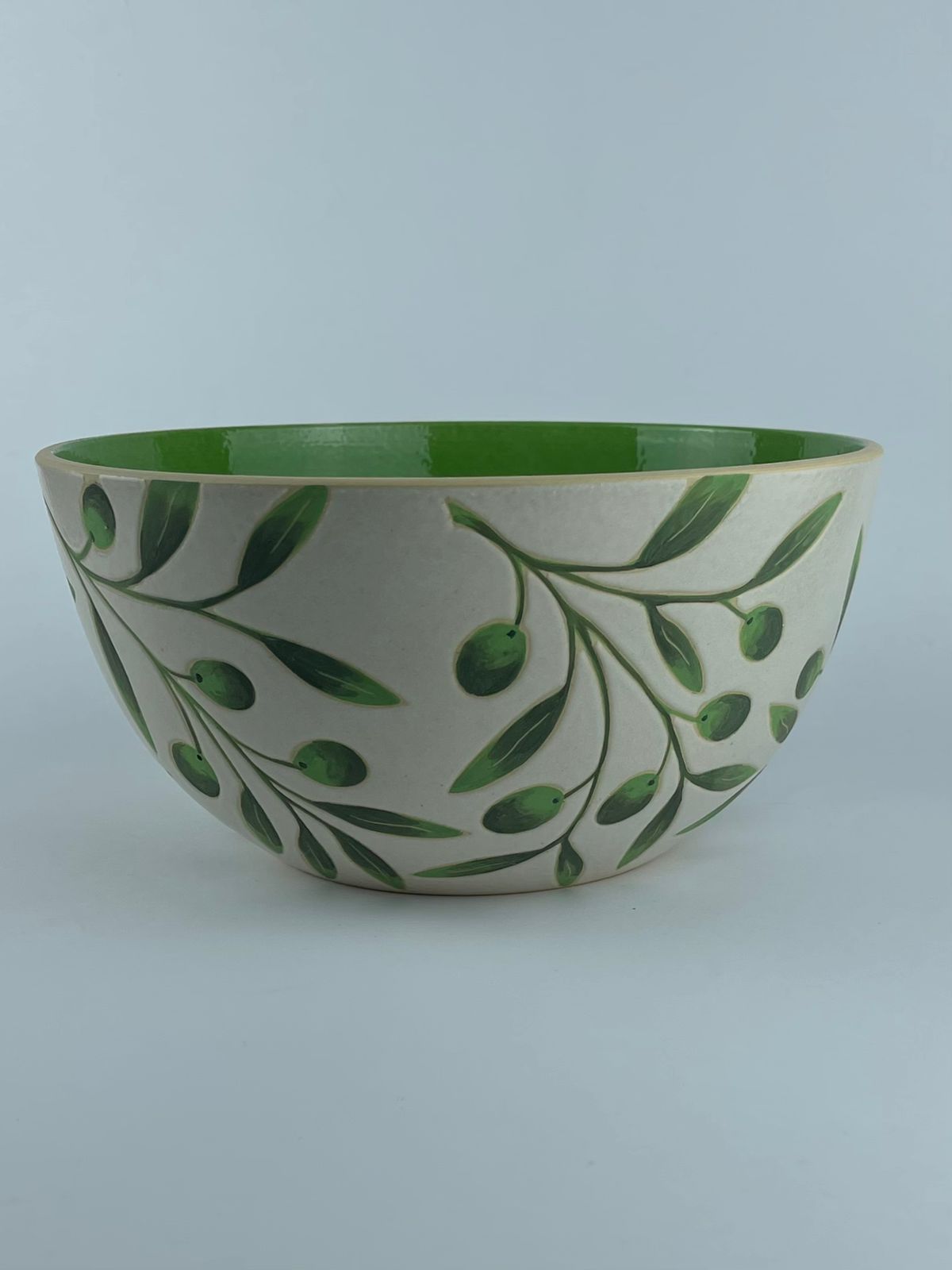 A U-shaped bowl with delicate olive branch and leaf motifs on a white background