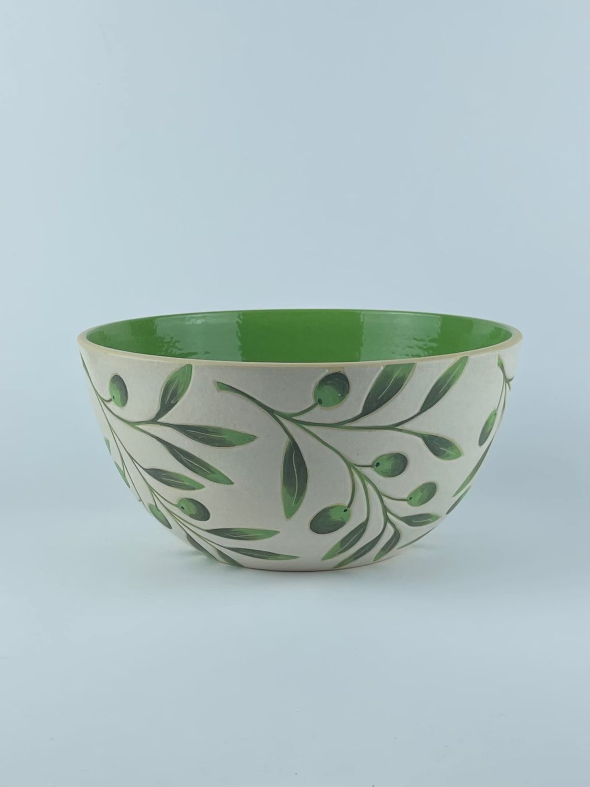 A U-shaped bowl with delicate olive branch and leaf motifs on a white background