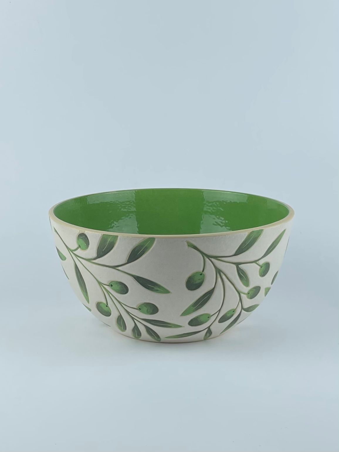 A U-shaped bowl with delicate olive branch and leaf motifs on a white background