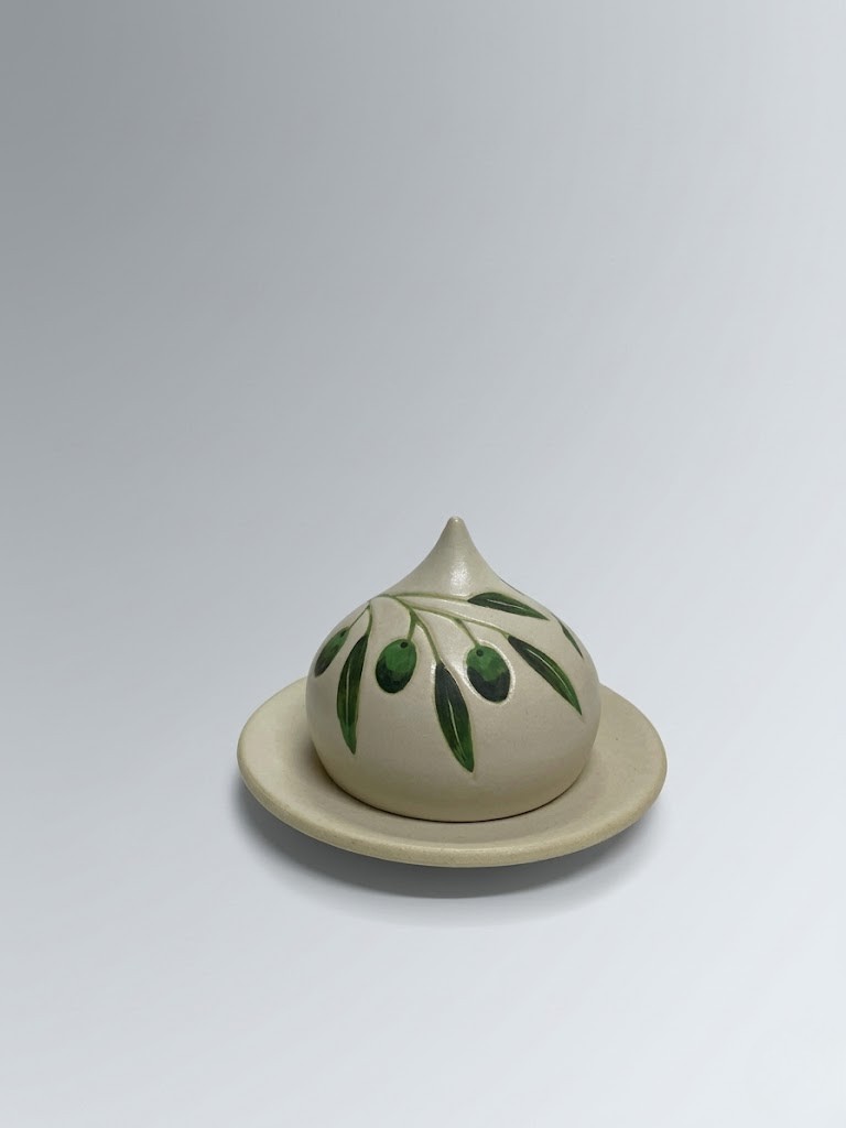 A mini cloche plate for treats. The lid features delicate olive branch and leaf motifs on a soft white surface