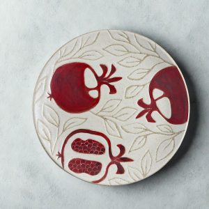 A dinner plate adorned with a red pomegranate motifs