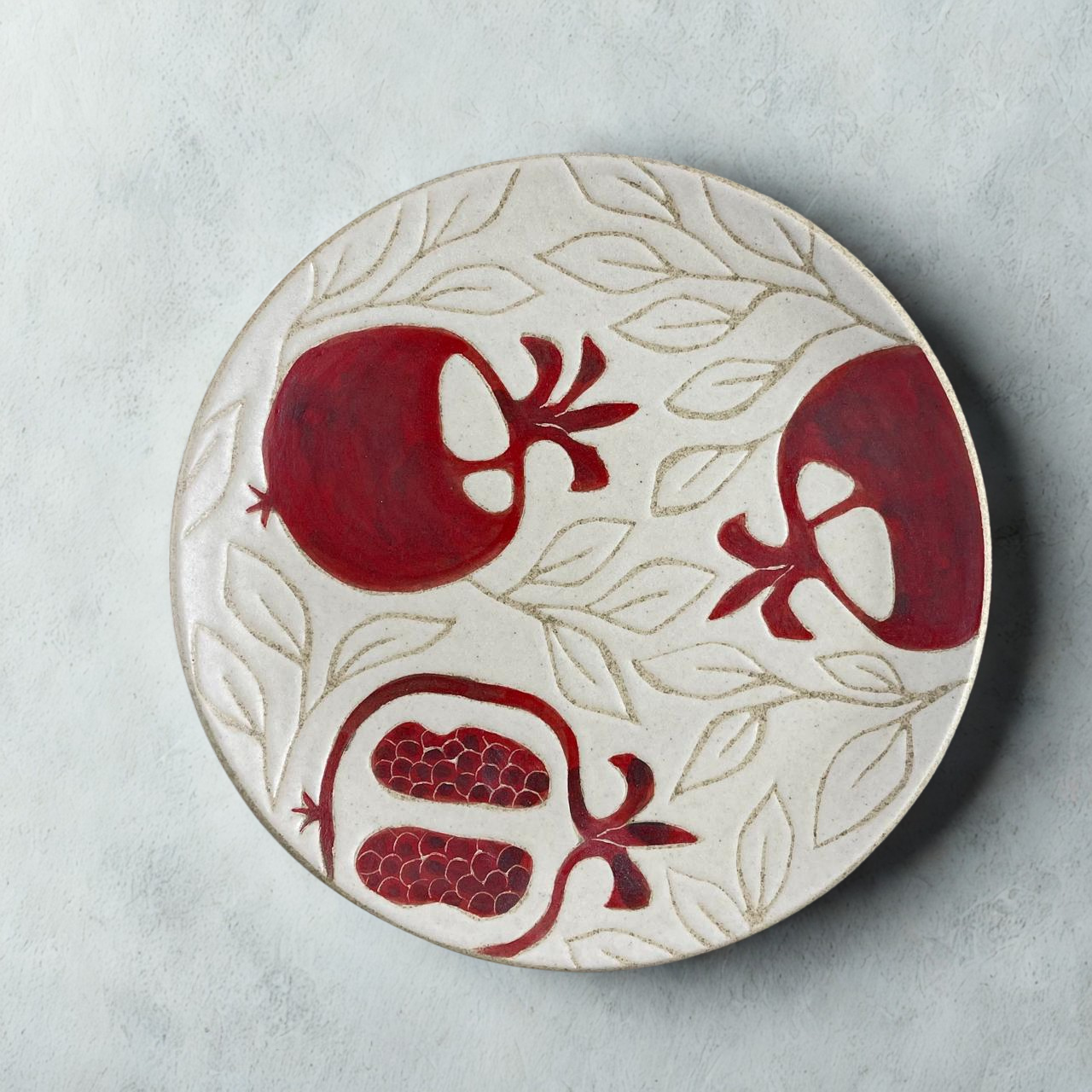 A dinner plate adorned with a red pomegranate motifs