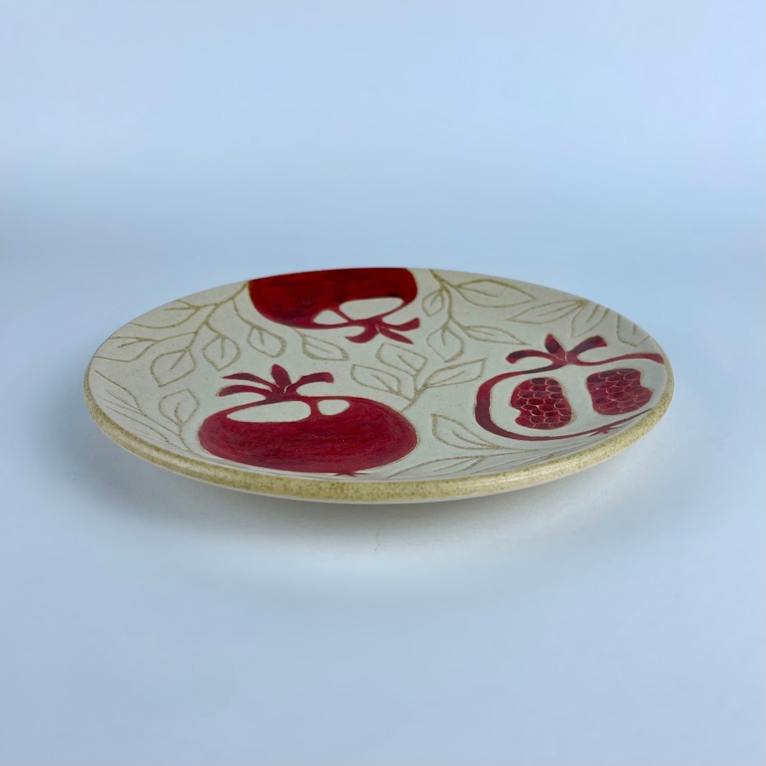 A serving plate decorated with a red pomegranate motifs