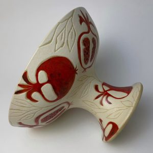 with a glossy red glazed interior. Designed for serving fruit