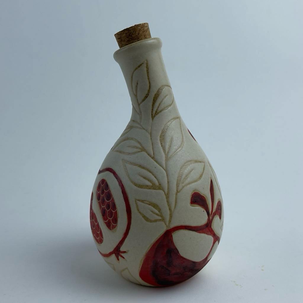A multi-use bottle featuring red pomegranate motifs. Suitable for serving oil