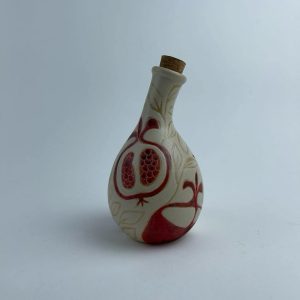 A multi-use bottle featuring red pomegranate motifs. Suitable for serving oil