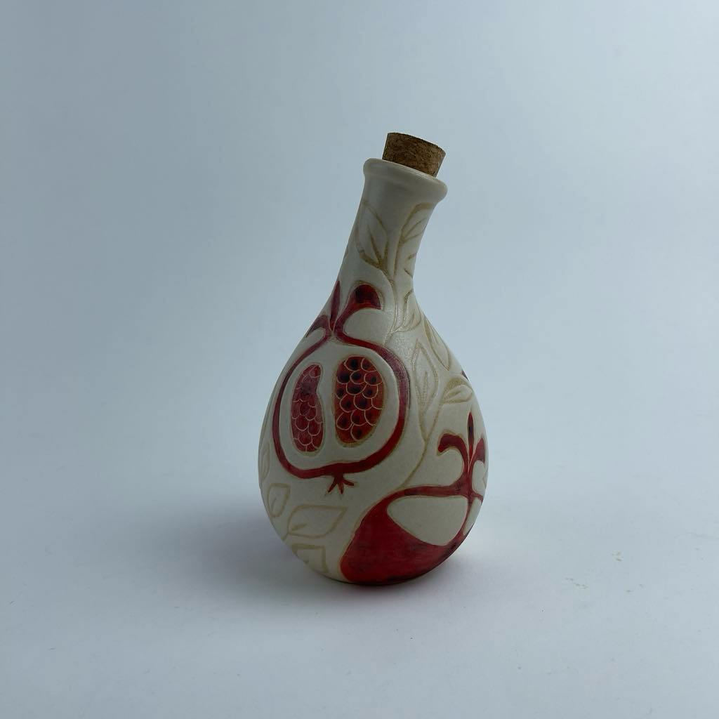 A multi-use bottle featuring red pomegranate motifs. Suitable for serving oil