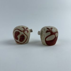 A set of two salt and pepper shakers featuring red pomegranate motifs