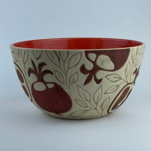 A U-shaped bowl featuring pomegranate motifs and a glossy red interior