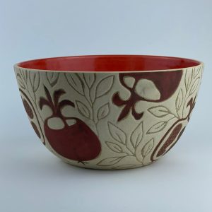 A U-shaped bowl featuring pomegranate motifs and a glossy red interior