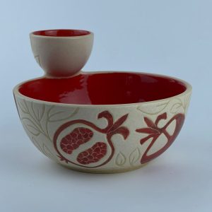 A two-section snack bowl featuring red pomegranate motifs