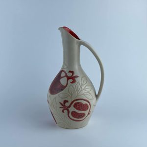 A handled pitcher adorned with a red pomegranate motifs