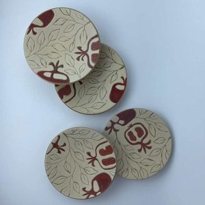 A set of four serving plates decorated with red pomegranate motifs