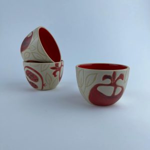 A set of four U-shaped snack bowls featuring red pomegranate motifs