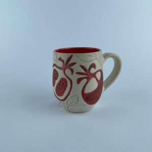 A U-shaped mug featuring a red pomegranate motifs for serving coffee and beverages.