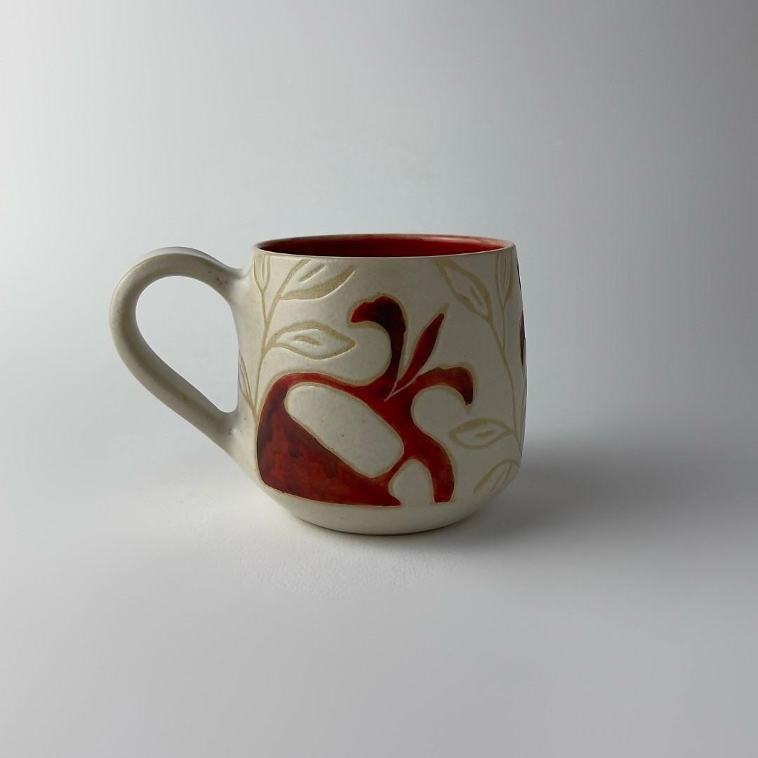 An edged mug featuring a red pomegranate motifs